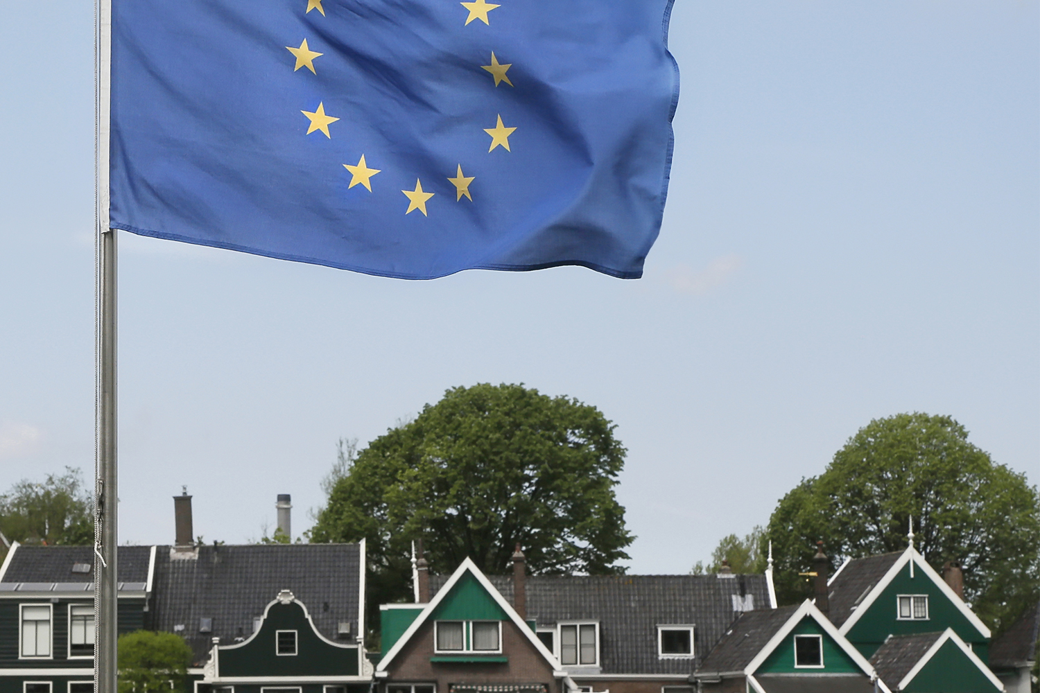 Een Europese vlag met op de achtergrond een Nederlands dorp.